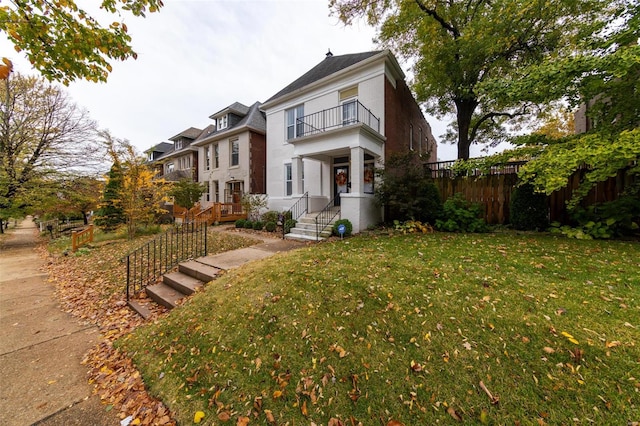 view of front of house featuring a balcony and a front lawn