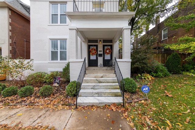 view of exterior entry with a porch and a balcony