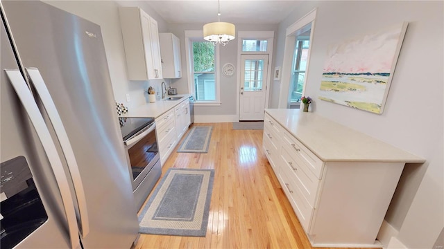 kitchen with white cabinetry, hanging light fixtures, stainless steel appliances, a chandelier, and light wood-type flooring