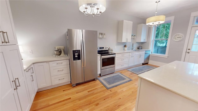 kitchen with pendant lighting, light hardwood / wood-style flooring, appliances with stainless steel finishes, white cabinetry, and a chandelier