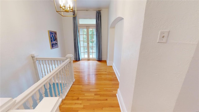 corridor with hardwood / wood-style flooring and an inviting chandelier