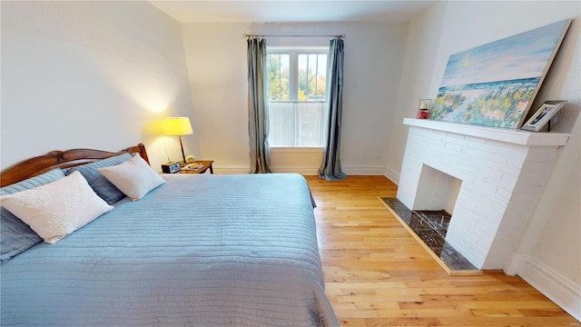 bedroom with a fireplace and light wood-type flooring