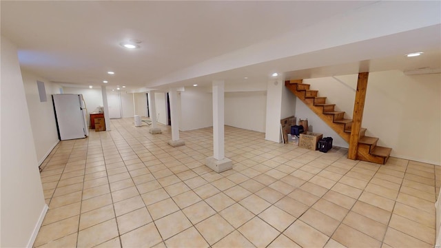 basement featuring white fridge and light tile patterned floors