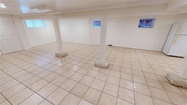 basement featuring white refrigerator and light tile patterned floors