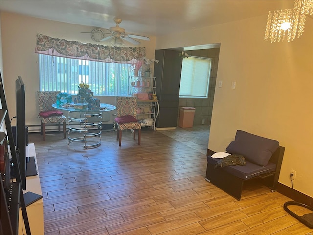 interior space with ceiling fan with notable chandelier, light hardwood / wood-style flooring, and baseboard heating