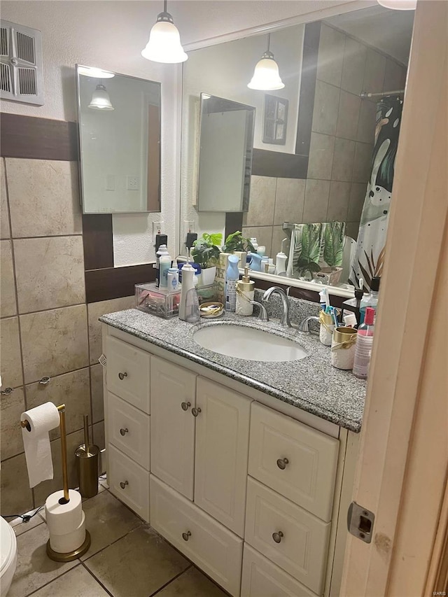 bathroom featuring tile patterned floors, vanity, tile walls, and toilet