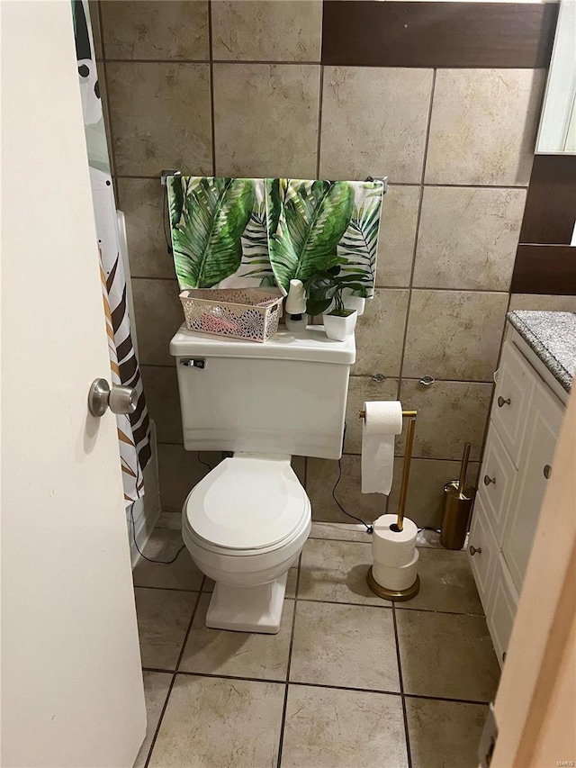 bathroom with tile patterned flooring, toilet, and tile walls