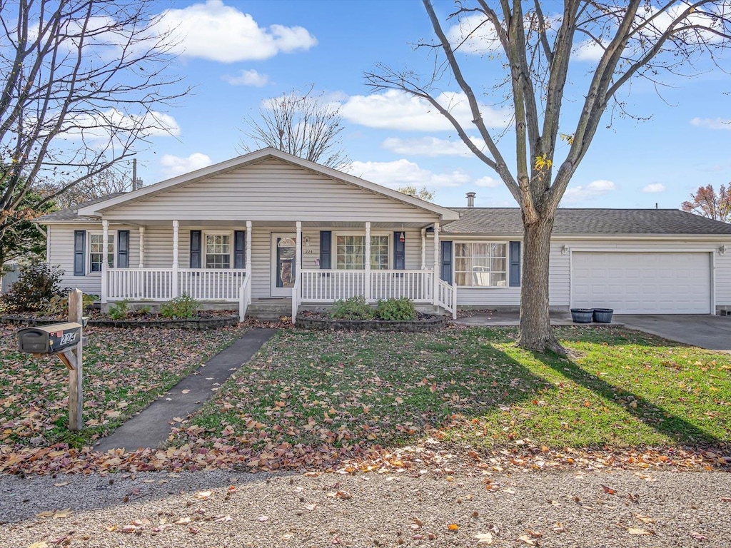 single story home featuring covered porch, a garage, and a front yard