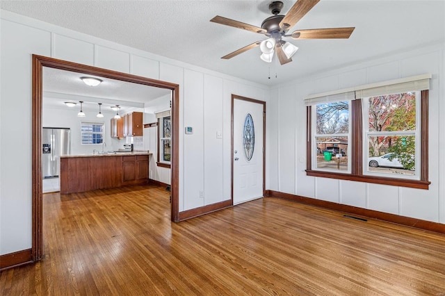 entrance foyer featuring a textured ceiling, light hardwood / wood-style floors, plenty of natural light, and ceiling fan