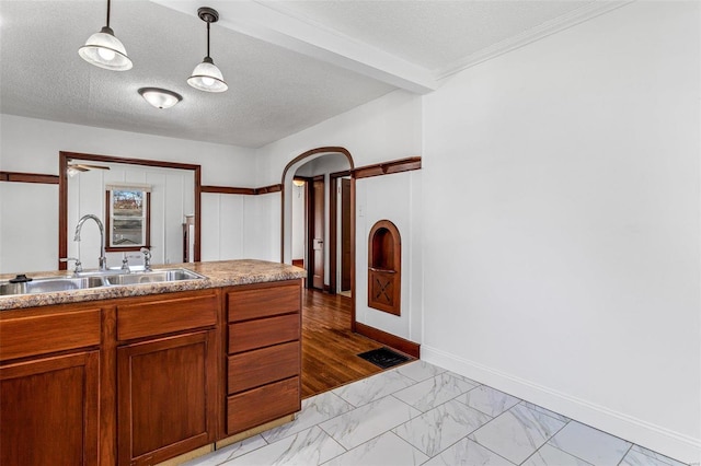 kitchen with crown molding, sink, hanging light fixtures, a textured ceiling, and light hardwood / wood-style floors