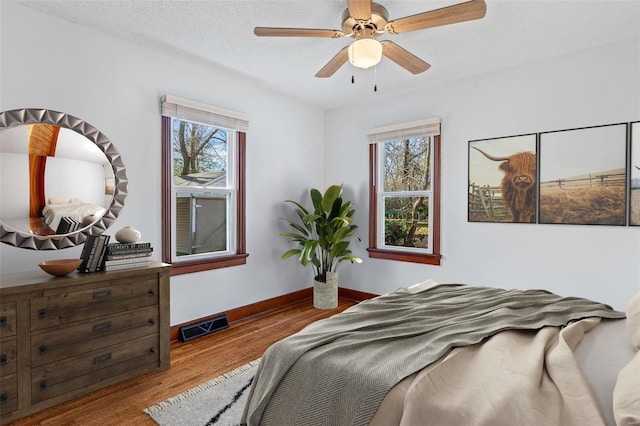 bedroom with ceiling fan, light wood-type flooring, and a textured ceiling