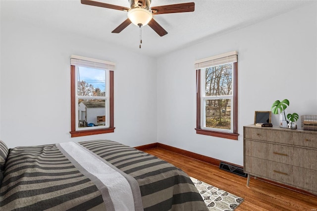 bedroom featuring light hardwood / wood-style flooring, multiple windows, and ceiling fan