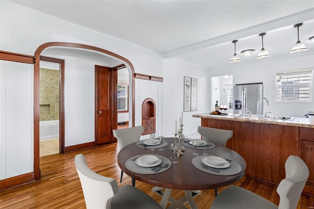 dining space featuring ornamental molding, a textured ceiling, dark wood-type flooring, and sink