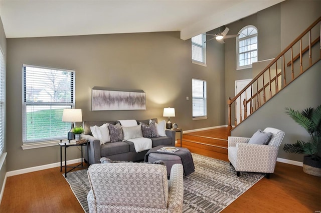 living room featuring ceiling fan, a wealth of natural light, beamed ceiling, and hardwood / wood-style flooring