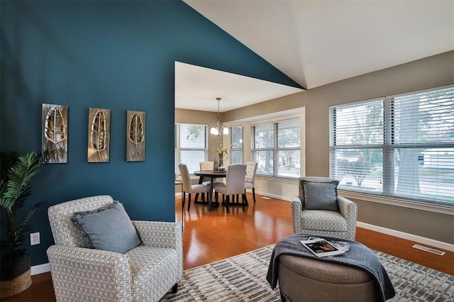 living room featuring hardwood / wood-style flooring, an inviting chandelier, and vaulted ceiling