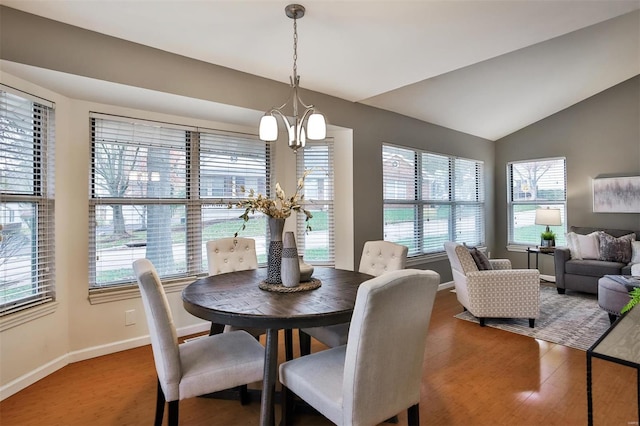 dining space with a chandelier, wood-type flooring, and vaulted ceiling