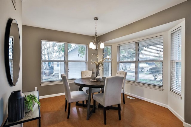 dining area featuring dark wood-type flooring and an inviting chandelier