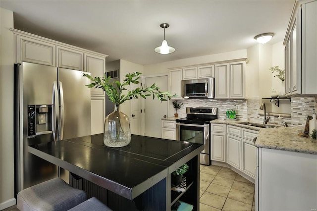 kitchen with sink, light stone counters, pendant lighting, decorative backsplash, and appliances with stainless steel finishes