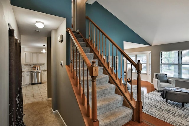 stairway with tile patterned floors and vaulted ceiling