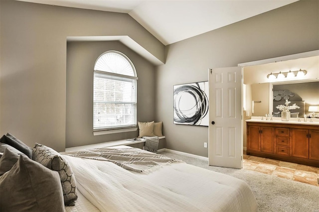 carpeted bedroom featuring ensuite bath, sink, and vaulted ceiling