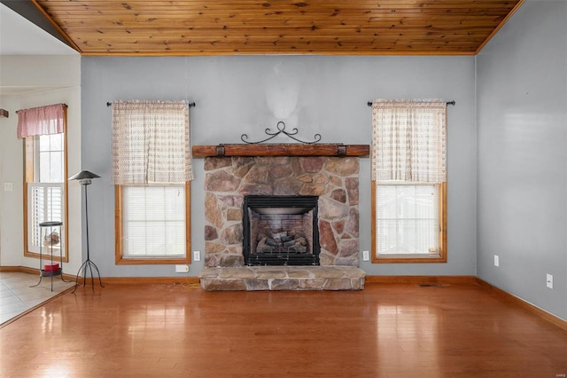 unfurnished living room featuring hardwood / wood-style flooring, a stone fireplace, and wooden ceiling