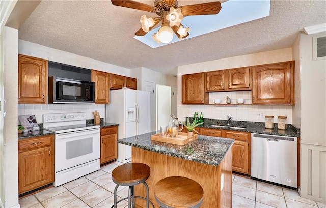 kitchen featuring light tile patterned flooring, sink, white appliances, and a kitchen island