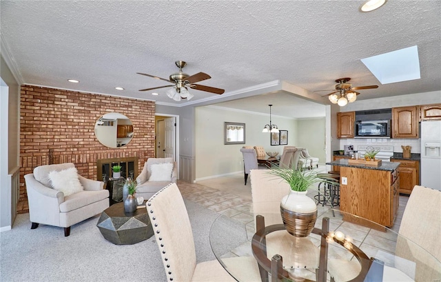 living room featuring a textured ceiling, a fireplace, a skylight, and ornamental molding