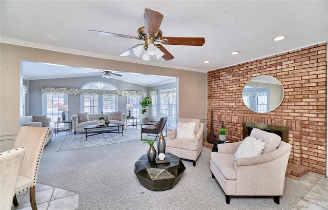 living room with ceiling fan, vaulted ceiling, a fireplace, and crown molding