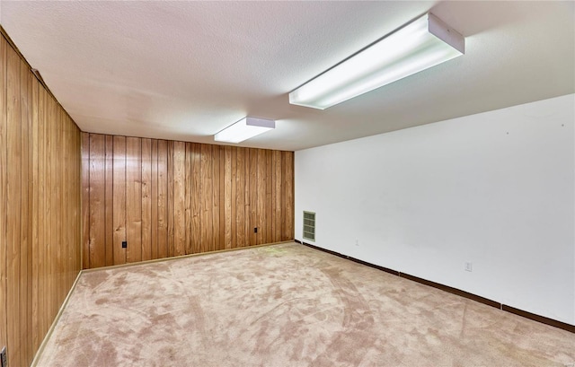 carpeted empty room featuring wood walls and a textured ceiling