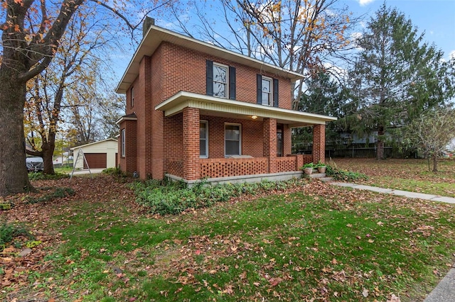 front of property featuring a front lawn, covered porch, an outdoor structure, and a garage