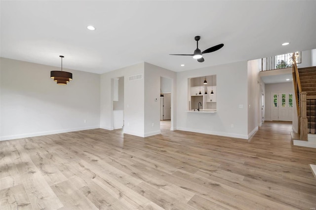 unfurnished living room featuring ceiling fan and light wood-type flooring