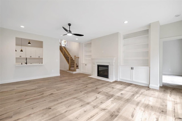 unfurnished living room with ceiling fan, light hardwood / wood-style floors, built in features, and sink