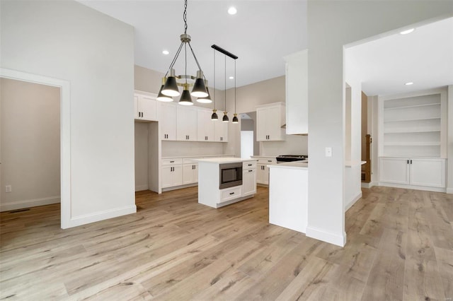 kitchen featuring pendant lighting, a kitchen island, white cabinetry, and light hardwood / wood-style flooring