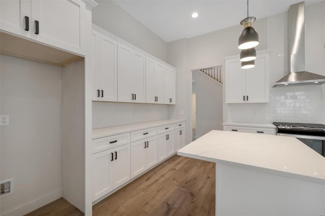 kitchen featuring light hardwood / wood-style flooring, white cabinets, hanging light fixtures, and wall chimney range hood