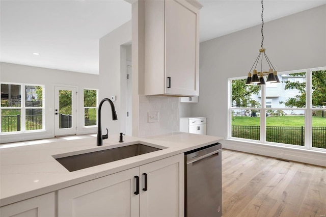 kitchen with stainless steel dishwasher, white cabinets, sink, and light hardwood / wood-style flooring