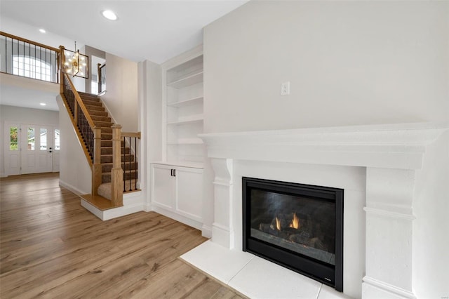 unfurnished living room with built in features and light hardwood / wood-style flooring