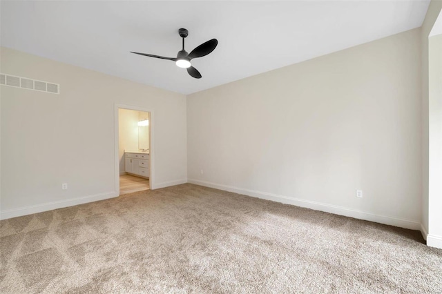 unfurnished bedroom featuring ceiling fan, light colored carpet, and ensuite bath