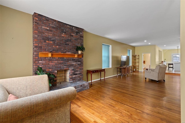 living room with wood-type flooring and a brick fireplace