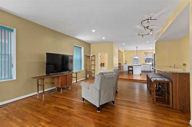 living room with track lighting, plenty of natural light, and dark wood-type flooring