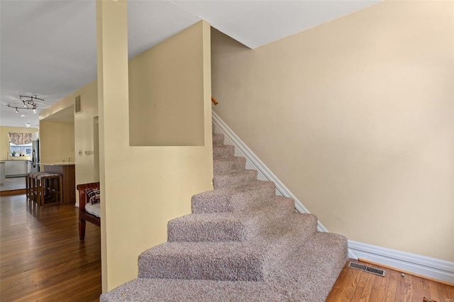 stairs featuring hardwood / wood-style floors and track lighting