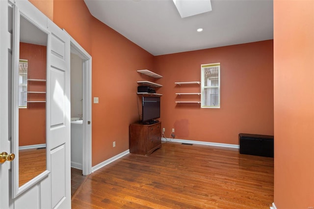 unfurnished office featuring wood-type flooring and a skylight