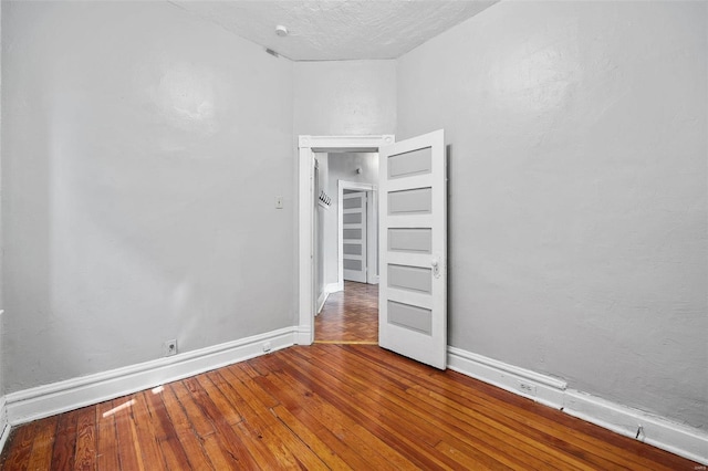 unfurnished room with wood-type flooring and a textured ceiling