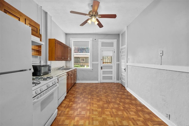 kitchen featuring sink, white appliances, backsplash, and light parquet flooring