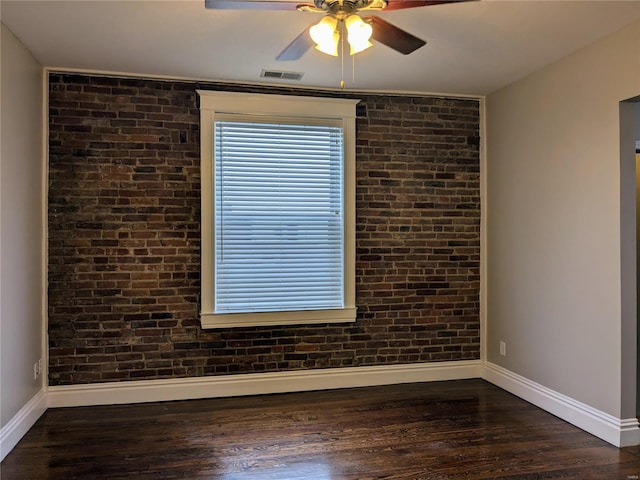 empty room with ceiling fan, brick wall, and dark hardwood / wood-style floors