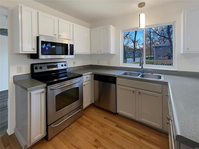 kitchen featuring white cabinets, appliances with stainless steel finishes, light wood-type flooring, and pendant lighting