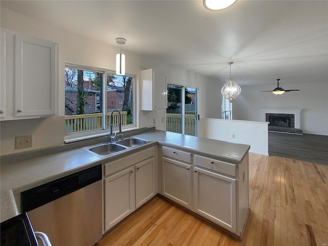 kitchen with dishwasher, white cabinets, sink, hanging light fixtures, and kitchen peninsula