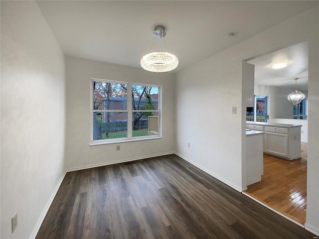 unfurnished dining area featuring dark wood-type flooring and a notable chandelier