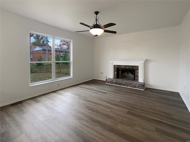 unfurnished living room featuring dark hardwood / wood-style flooring, a brick fireplace, and ceiling fan