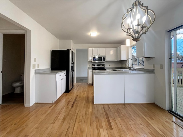 kitchen with hanging light fixtures, appliances with stainless steel finishes, white cabinetry, and plenty of natural light