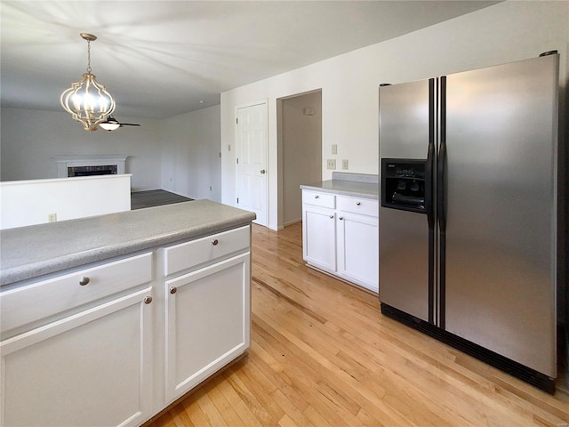 kitchen featuring stainless steel fridge with ice dispenser, light hardwood / wood-style floors, white cabinetry, and decorative light fixtures